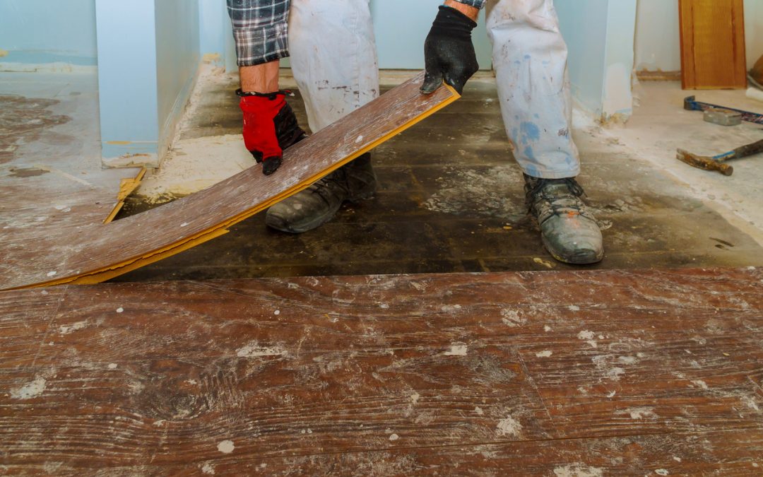 Worker pulling up laminate flooring installation